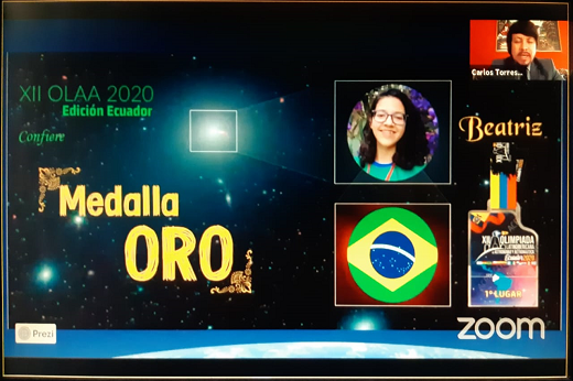 Imagem: Banner do evento, com o texto "medalha de ouro", o rosto da estudante Beatriz Rodrigues e a bandeira do Brasil (Imagem: Divulgação/OLAA 2020)