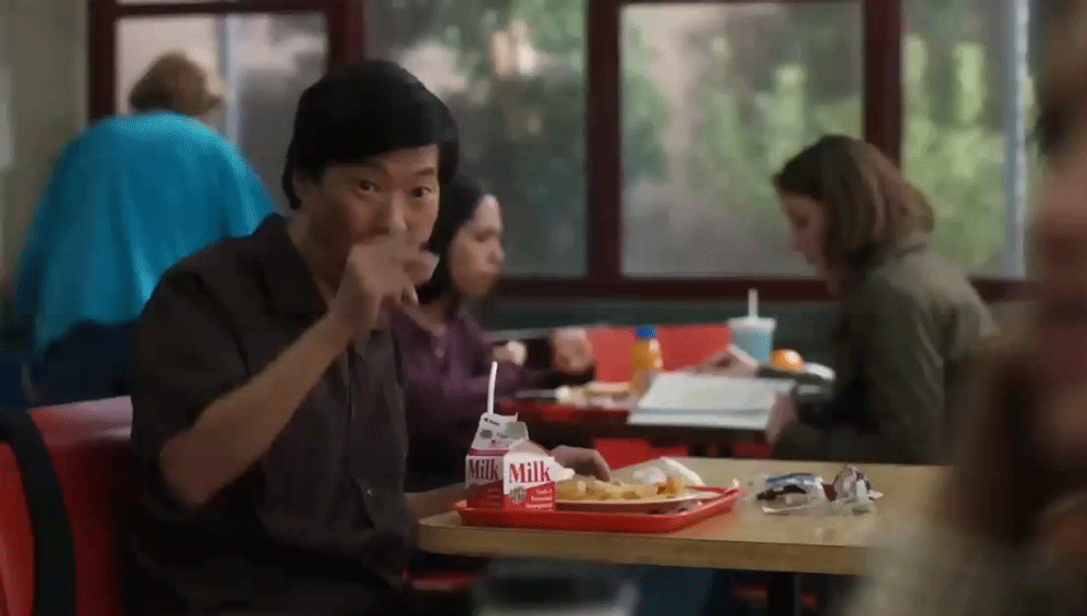 Personagem da série Community estala os dedos diante de bandeja de comida