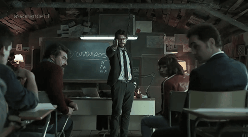 Personagem Professor, da série La Casa de Papel, aponta para o fundo de uma sala enquanto os outros personagens olham para trás