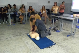 Imagem de instrutor ensinando estudantes a fazer massagem cardiorespiratória em boneco