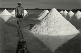 Imagem: Salinas, com um homem caminhando entre as montanhas de sal