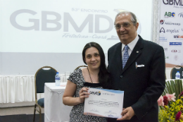 Imagem: A dentista Flávia Gonçalves recebeu prêmio das mãos do Prof. Júlio Jorge Lóssio (Foto: Viktor Braga/UFC)