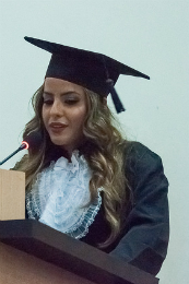 Imagem: Foto da concludente Bianca Lopes falando no microfone aos colegas e ao público da colação