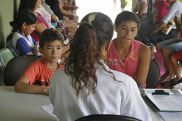 Imagem: Profissional de saúde recebendo pacientes em uma mesa de recepção 