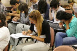 Imagem: Foto de estudantes sentados em carteiras resolvendo uma prova