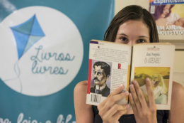 Imagem: Foto de uma moça com livro na mão em frente à logomarca do projeto