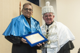 Imagem: Foto do Prof. Tarcísio Pequeno com o título de professor emérito nas mãos, ao lado dele, o reitor Henry Campos
