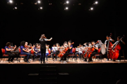 Imagem: foto da orquestra tocando em um palco
