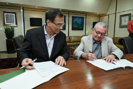 Imagem: Foto do presidente da FIEC, BetoStudart, e do reitor Henry Campos, sentados a uma mesa assinando os papéis do convênio