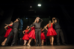 Imagem: foto de servidores dançando no palco do Teatro Universitário