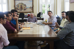 Imagem: Estudantes e profissionais sentados à mesa de reunião junto com reitor e Prof. Almir Holanda