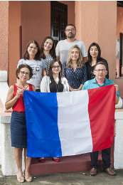 Imagem: foto dos professores da Casa de Cultura Francesa segurando a bandeira da França nas escadas da casa