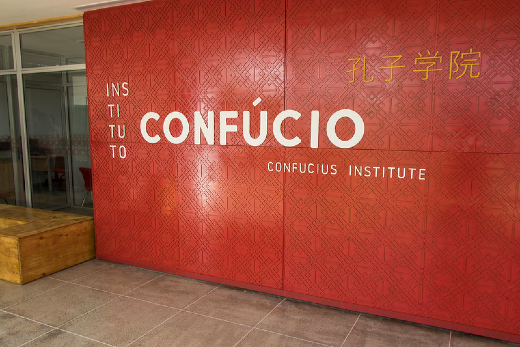 Foto da fachada do Instituto Confúcio na UFC com uma parede vermelha, os dizeres em branco e os ideogramas chineses escritos em amarelo