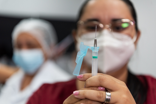 Imagem: Profissional de saúde segurando uma seringa contendo dose da vacina contra covid-19 (Foto: Viktor Braga/UFC)