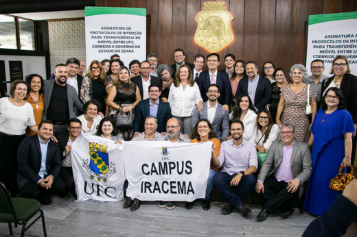 Imagem: Representantes da UFC posam portando bandeiras com o brasão da Universidade e a inscrição "Campus Iracema"