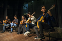 Imagem: foto de jovens tocando violão no palco do Teatro Universitário