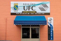 Imagem da porta de entrada da livraria das Edições UFC, uma porta de alumínio, uma marquise azul e a placa informativa