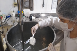 Imagem: foto de uma mulher de touca mexendo uma panela em laboratório