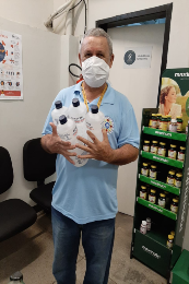 Imagem: foto de um senhor de máscara segurando embalagens de álcool