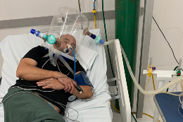 Paciente testa deitado o protótipo do elmo de respiração assistida 