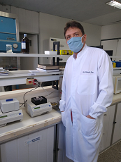 Imagem de um homem de jaleco e máscara em um laboratório
