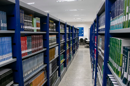 Foto de um corredor da biblioteca do Campus da UFC em Crateús, com estantes à esquerda e à direita