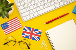 Imagem: ilustração com visão superior de uma mesa onde se vê um telado, um óculos, um lápis, um caderno e as bandeiras, em tamanho pequeno, dos Estados Unidos e da Inglaterra