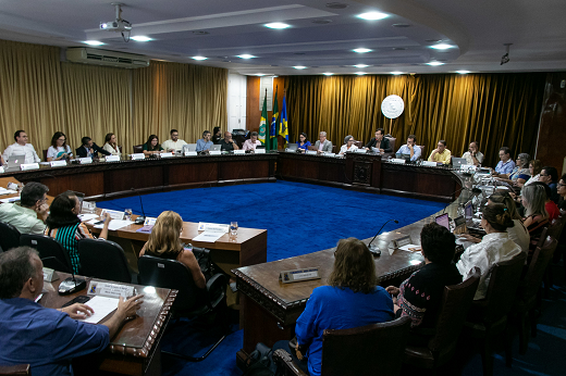 Imagem: Foto mostra o reitor Custódio Almeida (ao centro, de terno escuro) conduzindo reunião do Conselho Universitário; os conselheiros lotam o plenário. (Foto: Ribamar Neto/UFC Informa)
