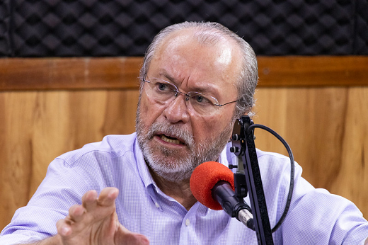 Imagem: foto do reitor Cândido Albuquerque falando ao microfone no estúdio da rádio Universitária FM