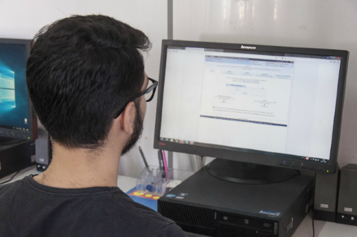 Imagem: estudante de frente a um computador com acesso ao SIGAA