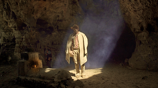 Cena do filme Encarnado: um homem com vestes de sertanejo, acampando dentro de uma caverna
