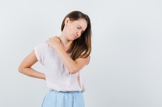 Imagem: mulher vestindo camisa branca e demisntrando sentir dor na coluna