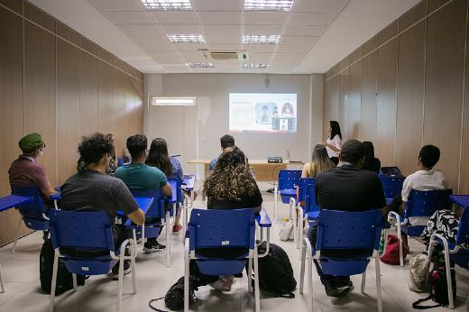 Imagem: sala com estudante apresentando trabalho