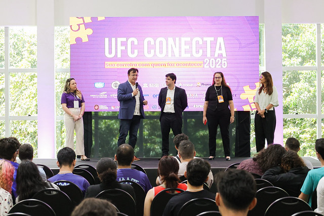 Imagem: cinco pessoas no palco com telão de LED ao fundo