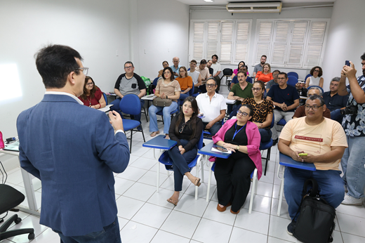 Imagem: De costas, reitor Custódio Almeida fala a estudantes da nova turma do Poleduc, sentados em um auditório