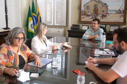 Pessoas reunidas na mesa de reunião do Gabinete da Reitoria