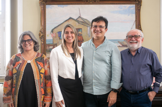 Quatro pessoas, entre elas o reitor, em pé, posando para a foto no Gabinete da Reitoria