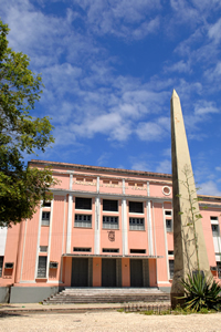 Foto da fachada principal do prédio da Faculdade de Direito com destaque para o Obelisco da Vitória.