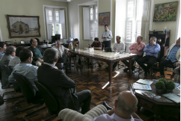 Imagem: foto de várias pessoas sentadas em cadeiras formando um círculo na sala do reitor