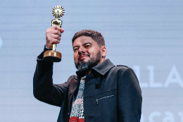 Foto do diretor do filme, Allan Deberton, levantando o troféu no festival