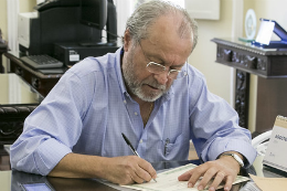 Imagem: homem branco sentando assinando documentos
