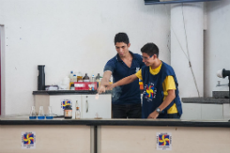 Imagem: foto de dois jovens em um balcão fazendo um experimento químico