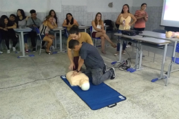 Imagem de instrutor ensinando estudantes a fazer massagem cardiorrespiratória em boneco