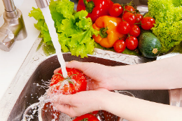 Imagem: Tomate sendo lavado numa pia de cozinha com água corrente da torneira