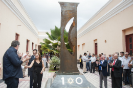 Imagem: foto de monumento do centenário e reitor e professores ao redor batendo palmas