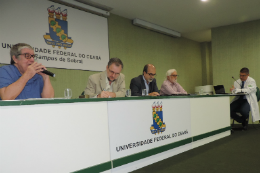 Imagem: Foto dos membros da banca examinadora atrás de uma mesa e o prof. Vicente à direita