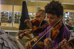 Imagem: Foto de dois homens em aula de violino, um mais velho e outro mais jovem