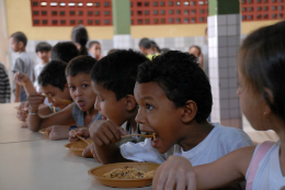 Crianças sentadas à mesa almoçando