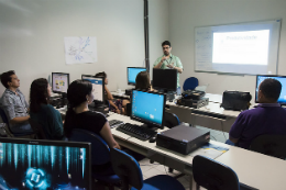 Imagem: foto de servidores em curso da Progep num laboratório de informática e professor à frente