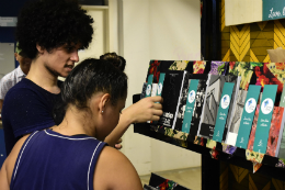 Imagem: Foto de um rapaz e uma moça pegando livros na estante do projeto Livros Livres
